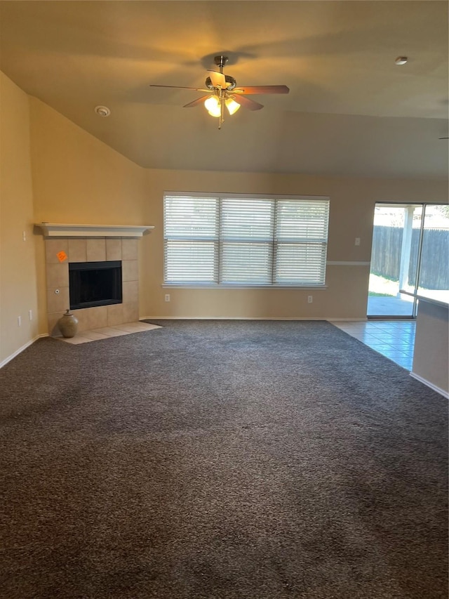 unfurnished living room featuring lofted ceiling, a tile fireplace, carpet flooring, and ceiling fan