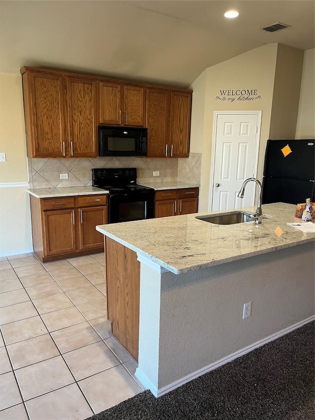 kitchen with sink, tasteful backsplash, light tile patterned floors, light stone countertops, and black appliances