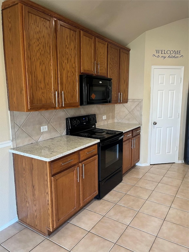 kitchen with light stone counters, decorative backsplash, light tile patterned floors, and black appliances