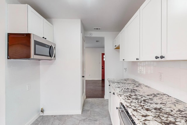 kitchen featuring white cabinetry, decorative backsplash, and light stone counters