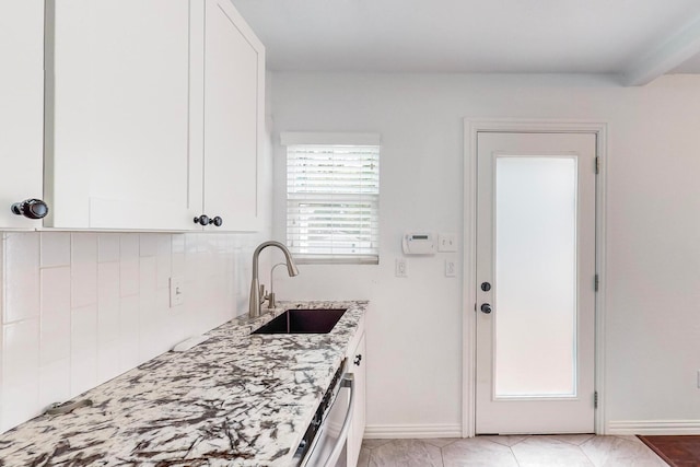 kitchen with white cabinetry, sink, light stone counters, and stainless steel dishwasher