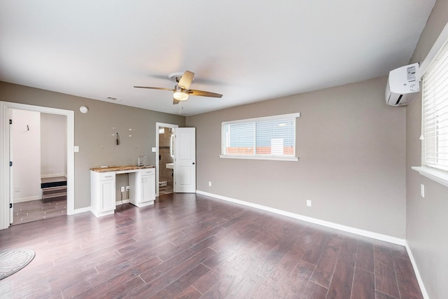 unfurnished living room featuring a wealth of natural light, an AC wall unit, ceiling fan, and dark hardwood / wood-style flooring