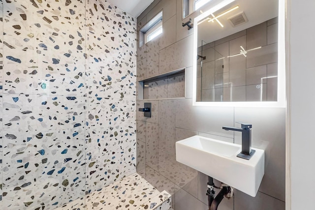 bathroom featuring tile walls, tiled shower, sink, and tile patterned floors