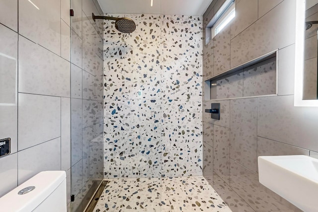 bathroom featuring toilet, tile walls, tile patterned flooring, and tiled shower