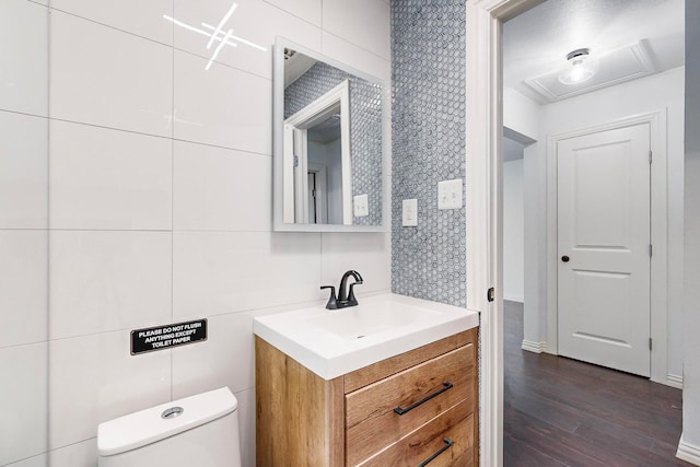 bathroom with tile walls, wood-type flooring, toilet, and vanity