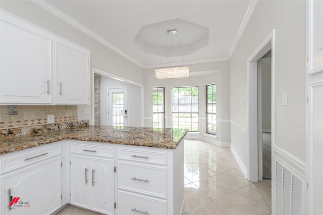 kitchen with white cabinets, a wealth of natural light, kitchen peninsula, and a tray ceiling