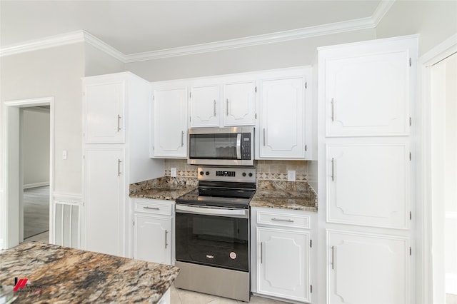 kitchen featuring white cabinets, decorative backsplash, appliances with stainless steel finishes, and dark stone countertops