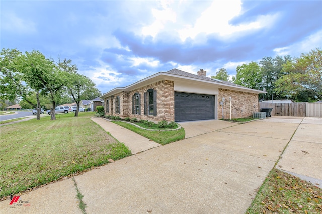 view of side of property featuring a lawn, central AC, and a garage