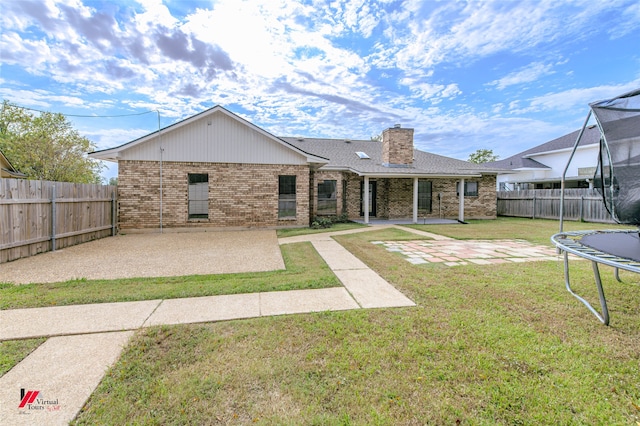 rear view of property with a patio area, a yard, and a trampoline