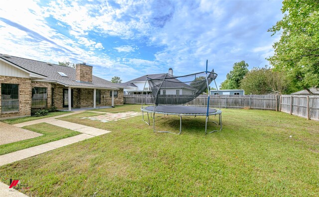 view of yard with a trampoline and a patio