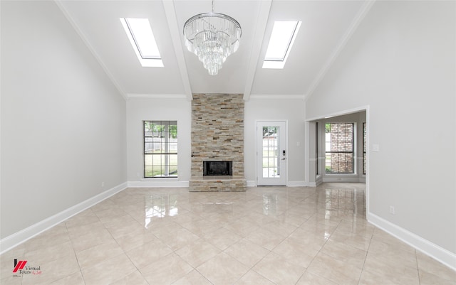 unfurnished living room with a chandelier, ornamental molding, high vaulted ceiling, a skylight, and a fireplace