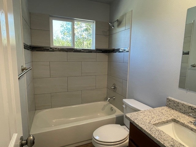 full bathroom featuring vanity, tiled shower / bath, and toilet