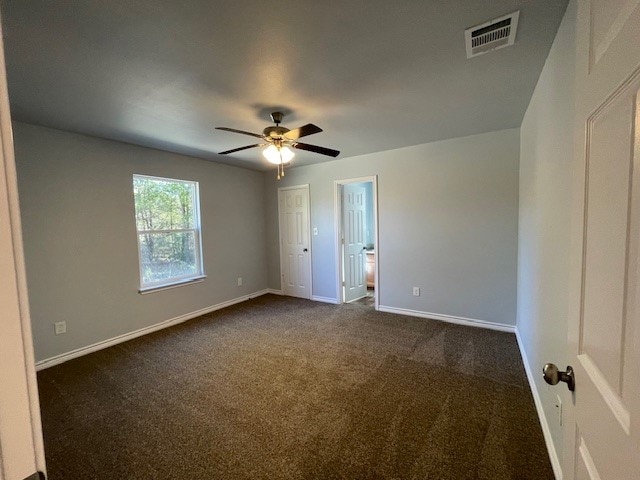 spare room featuring ceiling fan and dark colored carpet