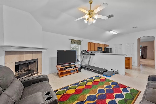 tiled living room featuring a fireplace, lofted ceiling, and ceiling fan