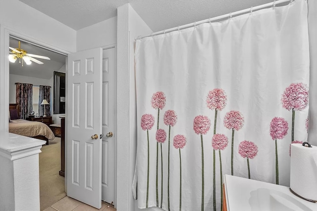 bathroom with ceiling fan, a textured ceiling, and tile patterned floors