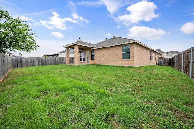 rear view of house with central AC and a lawn