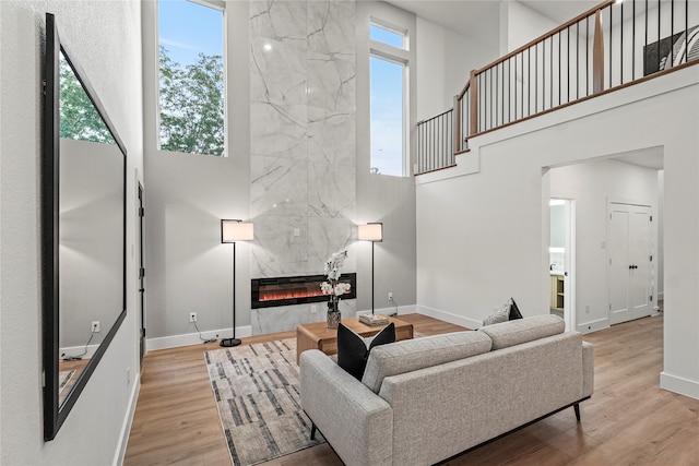 living room featuring a high ceiling, a tile fireplace, and light hardwood / wood-style floors