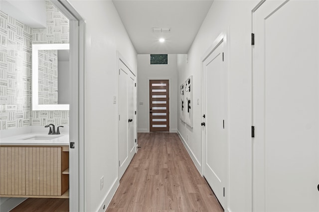 corridor featuring sink and light hardwood / wood-style flooring