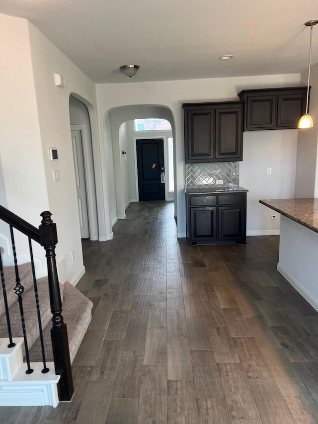 kitchen with hanging light fixtures, decorative backsplash, and dark wood-type flooring