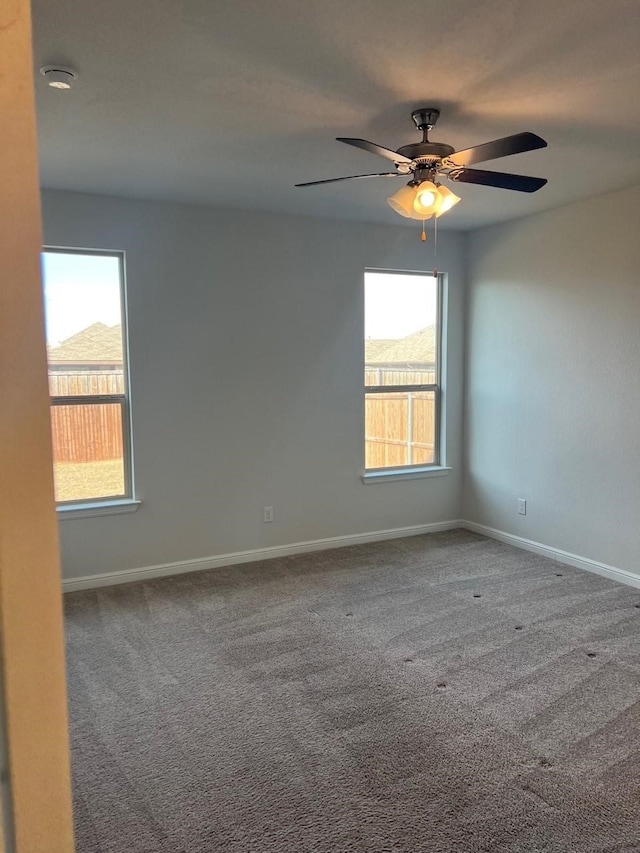 spare room featuring ceiling fan, carpet flooring, and a healthy amount of sunlight