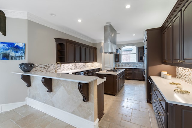 kitchen with a kitchen bar, kitchen peninsula, dark brown cabinetry, island exhaust hood, and backsplash