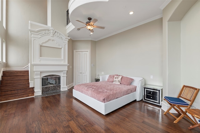 bedroom with ornamental molding, dark wood-type flooring, ceiling fan, and a closet