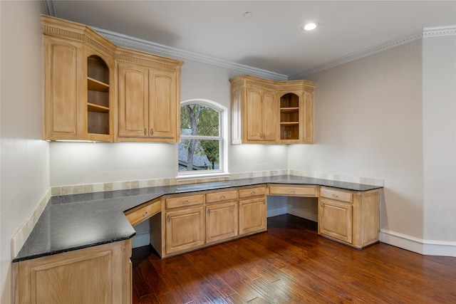 unfurnished office featuring dark wood-type flooring, built in desk, and ornamental molding