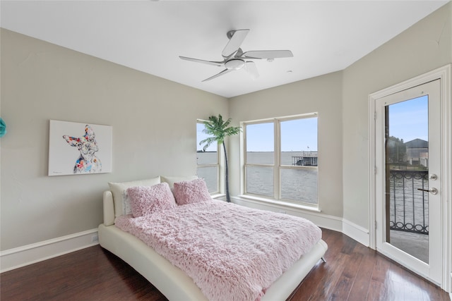 bedroom with ceiling fan, access to exterior, dark hardwood / wood-style floors, and a water view