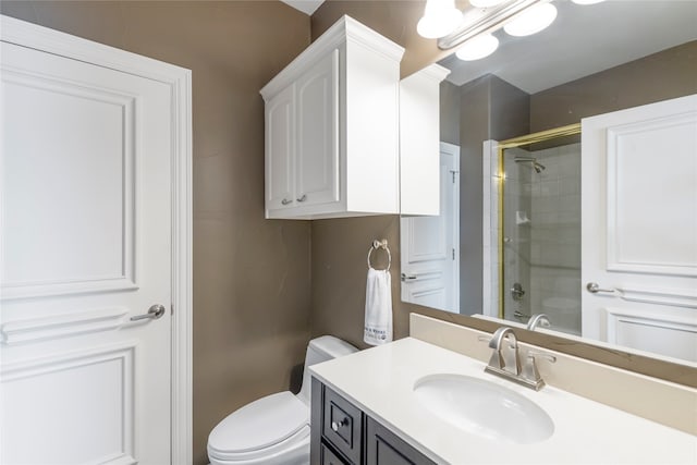 bathroom featuring a shower with door, vanity, and toilet