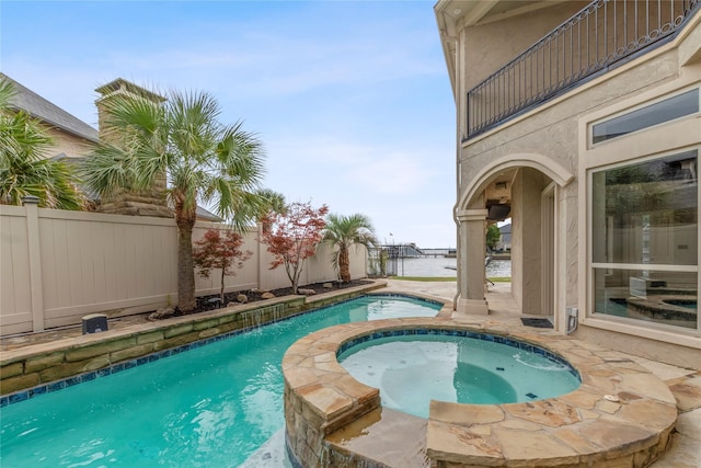 view of pool with an in ground hot tub and a water view