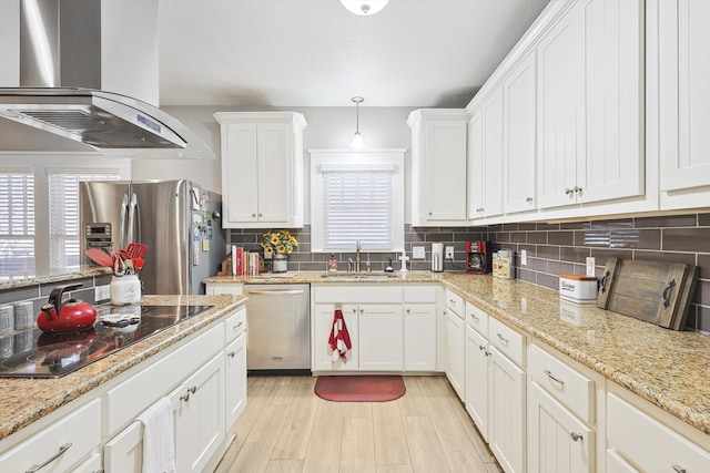 kitchen with white cabinetry, wall chimney range hood, appliances with stainless steel finishes, pendant lighting, and sink