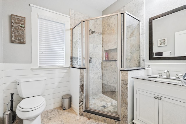 bathroom featuring wood walls, a shower with shower door, vanity, and toilet