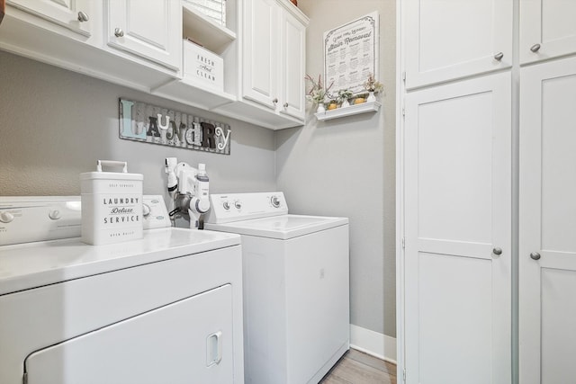 clothes washing area featuring separate washer and dryer, cabinets, and light wood-type flooring