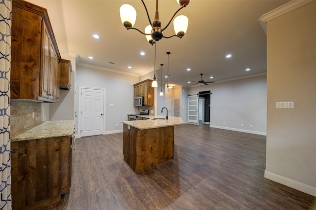 kitchen featuring stainless steel appliances, a barn door, sink, light stone countertops, and pendant lighting