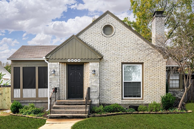 view of front of home with a front yard, board and batten siding, and brick siding