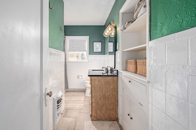 bathroom featuring vanity, tile patterned flooring, toilet, and tile walls