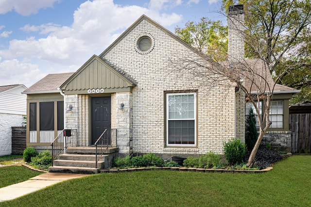 bungalow-style home featuring brick siding, a chimney, board and batten siding, and a front yard