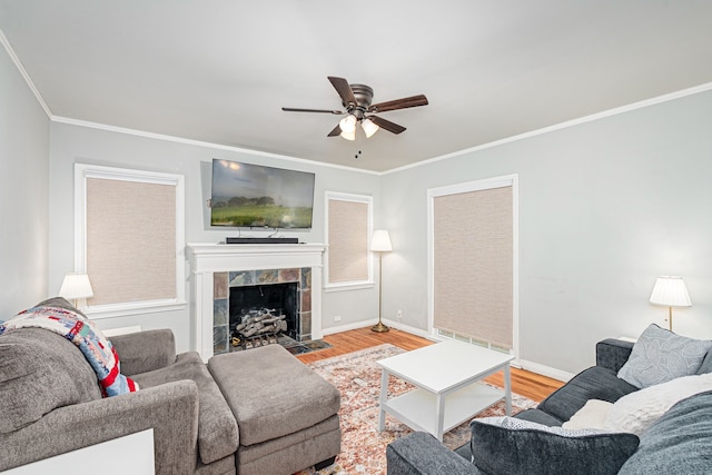 living room with ornamental molding, a fireplace, hardwood / wood-style flooring, and ceiling fan