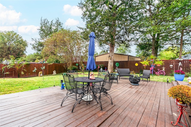 wooden deck featuring an outdoor fire pit and a lawn