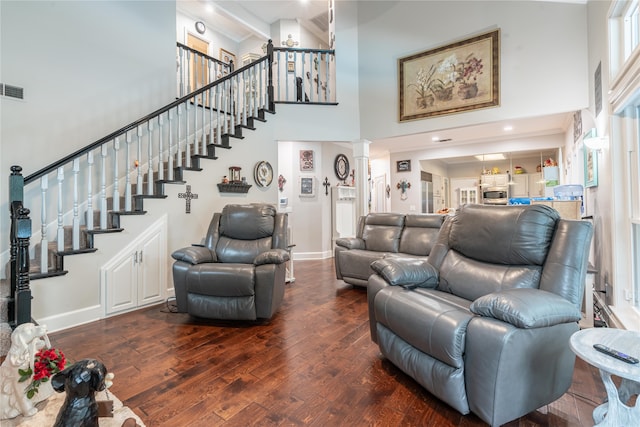 living room featuring dark hardwood / wood-style floors, a high ceiling, and decorative columns