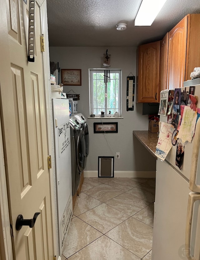 laundry room with cabinets, a textured ceiling, washer and dryer, and light tile patterned floors