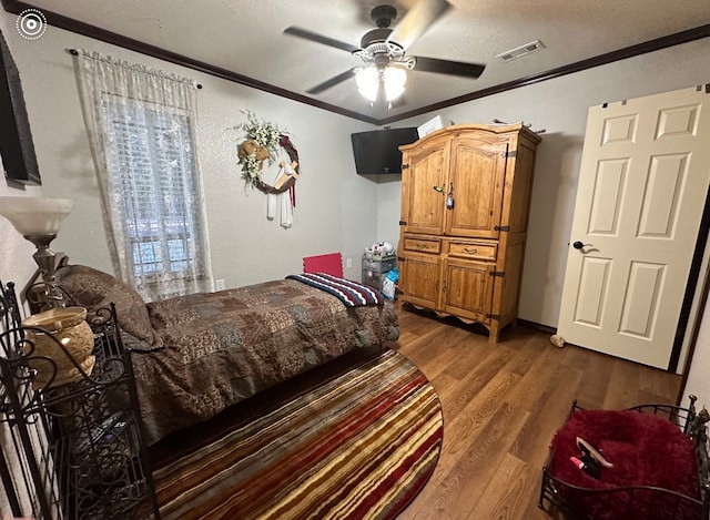 bedroom with a textured ceiling, dark hardwood / wood-style flooring, ceiling fan, and crown molding