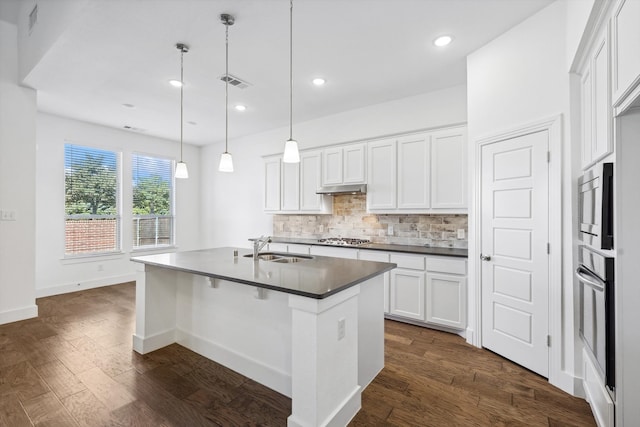 kitchen featuring sink, dark hardwood / wood-style flooring, an island with sink, pendant lighting, and white cabinets