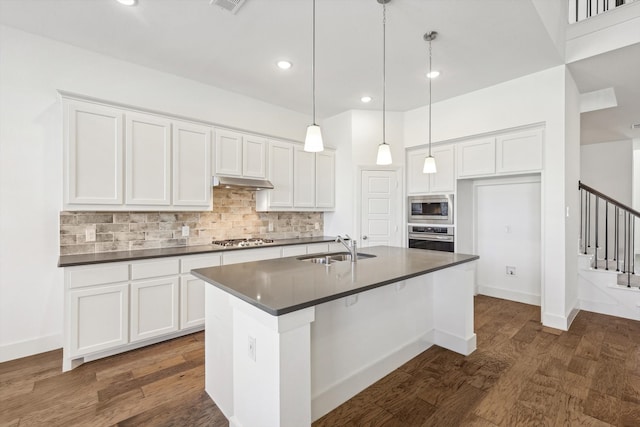 kitchen featuring white cabinets, stainless steel appliances, and a kitchen island with sink