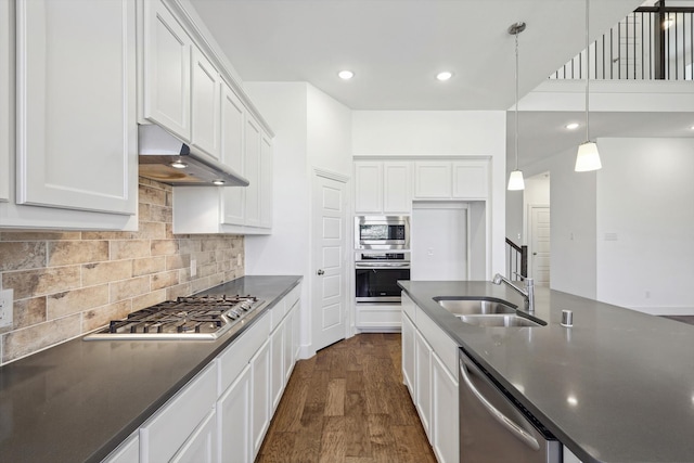 kitchen with appliances with stainless steel finishes, dark wood-type flooring, sink, pendant lighting, and white cabinets