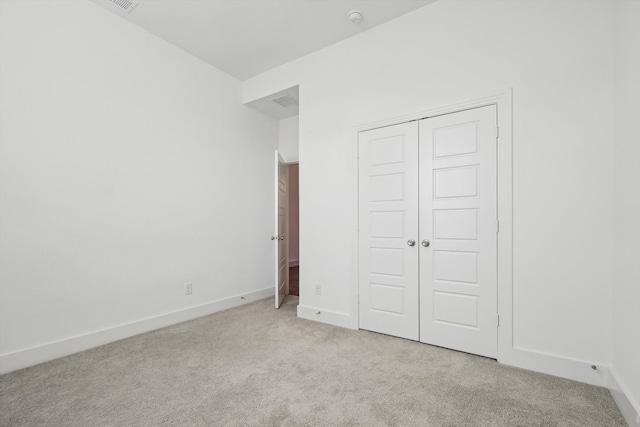 unfurnished bedroom featuring light carpet and a closet