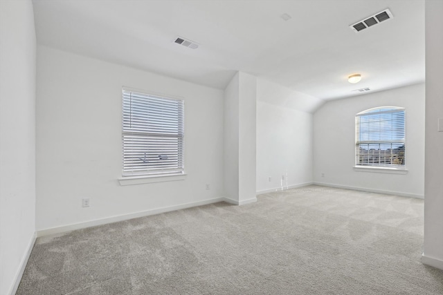 spare room featuring light colored carpet and vaulted ceiling