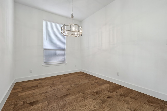 spare room featuring dark hardwood / wood-style floors and an inviting chandelier