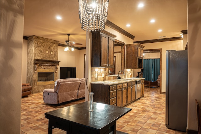 kitchen featuring stainless steel appliances, sink, backsplash, a fireplace, and crown molding