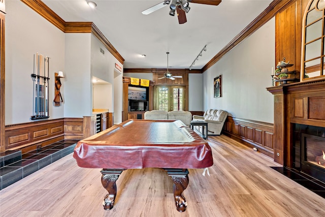 playroom featuring pool table, a tiled fireplace, hardwood / wood-style flooring, ceiling fan, and crown molding